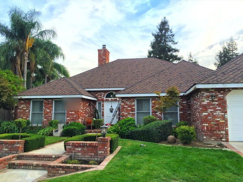 Brick ranch home with palm trees featuring a recently installed DeHart roof