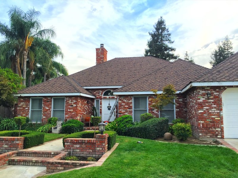 Completed roof on a brick ranch home with palm trees
