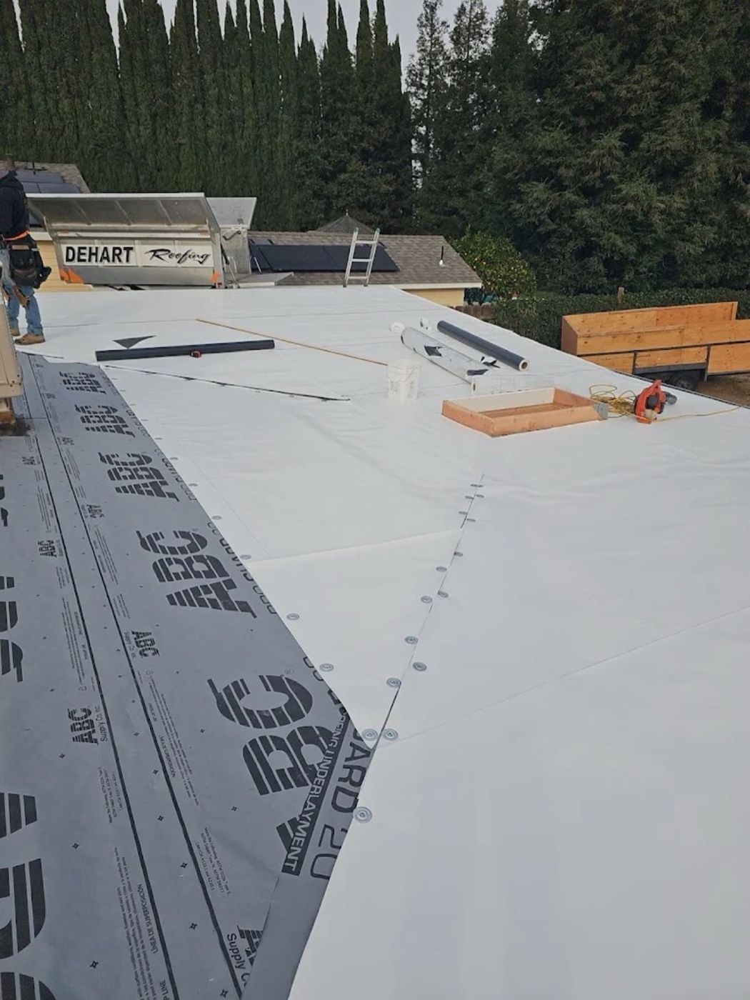 DeHart Roofing crew installing TPO single-ply membrane on a Stanislaus County commercial roof