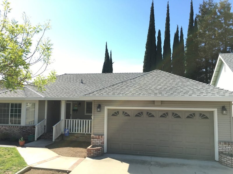 Completed charcoal-shingle re-roof on a two-story home with prominent gables in Turlock