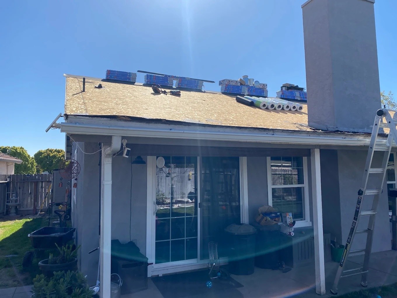 DeHart crew tearing off old shingles on a single-story Turlock home, mid-replacement